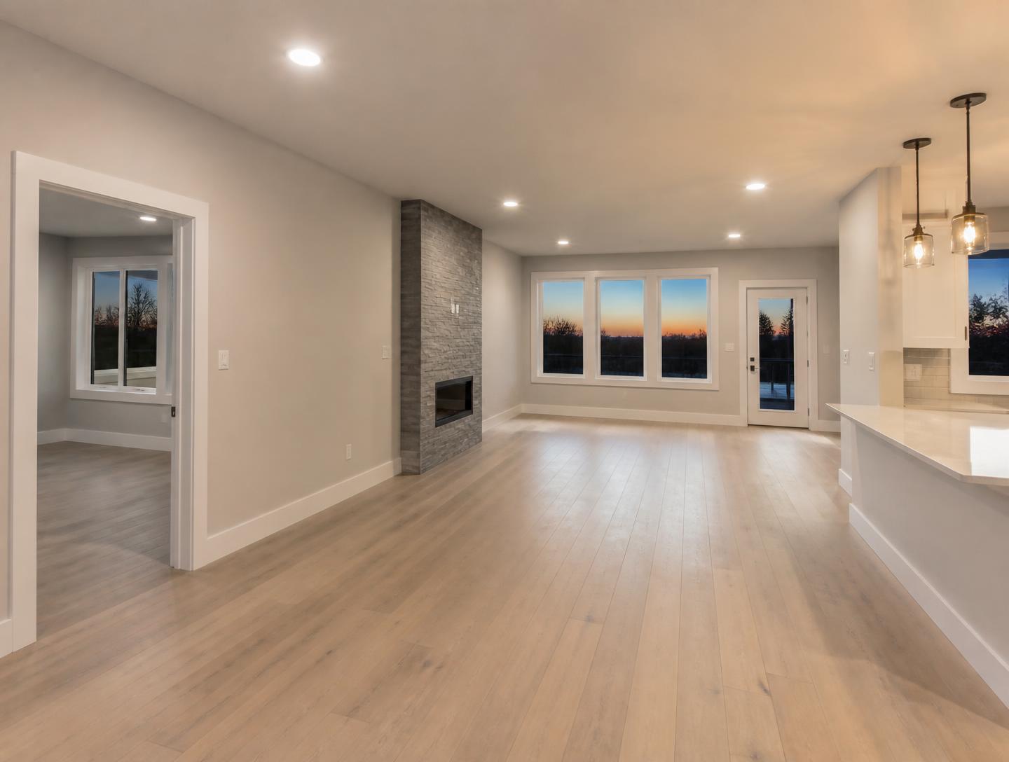 Spotless remodeled open-plan living area with flawless paint, wide-plank flooring, new windows and warm ambient lighting at dusk